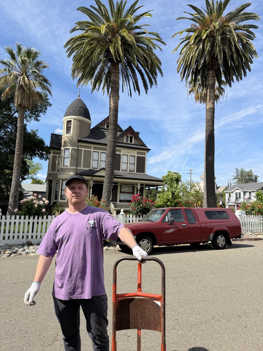 Smiling Lynx Movers crew member in a purple Lynx shirt with a hand truck