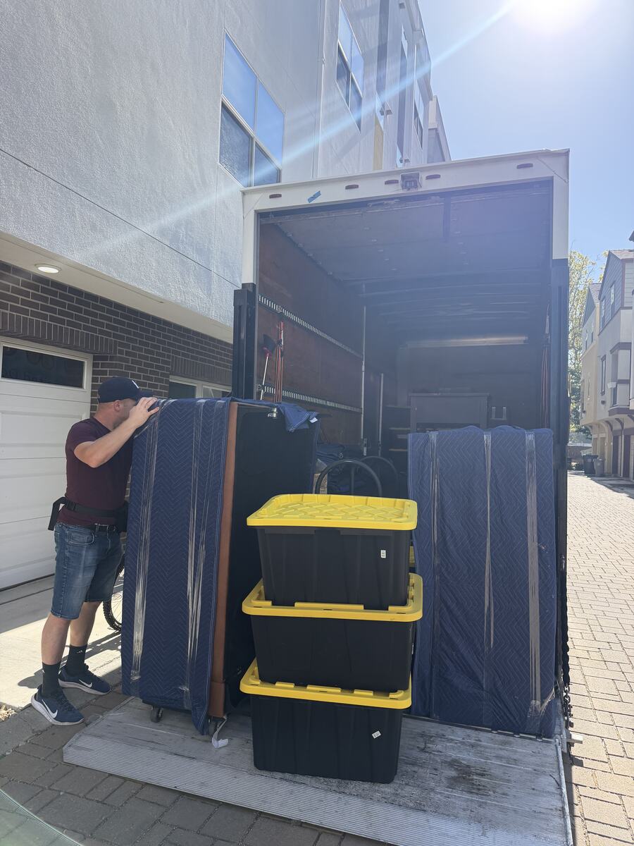 Lynx Movers crew loading blanket-wrapped furniture and totes into the truck